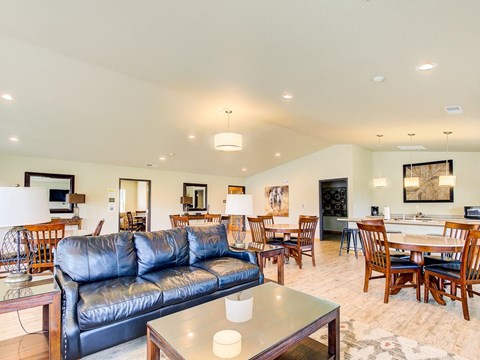 A living room with a black leather couch and wooden furniture.