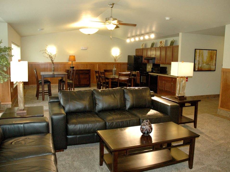 A black leather couch sits in a living room with a wooden coffee table in front of it.