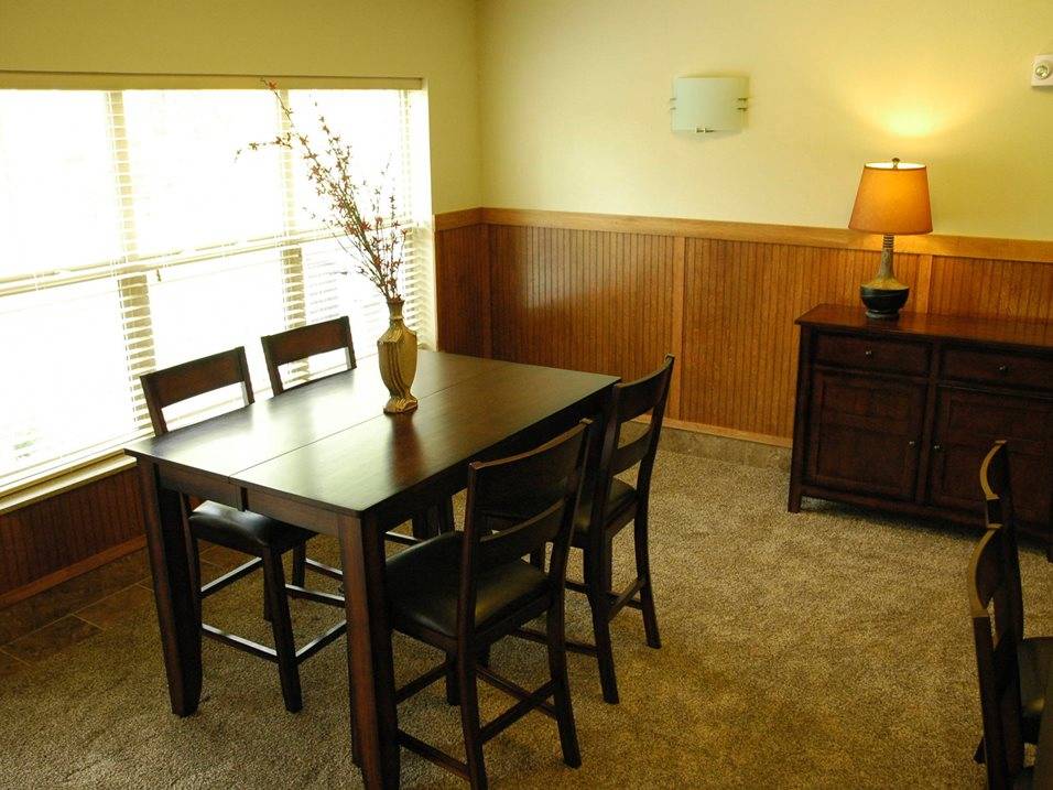 A dining room with a table, chairs, and a lamp.