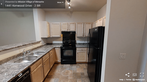 A kitchen with a black refrigerator and a black oven.