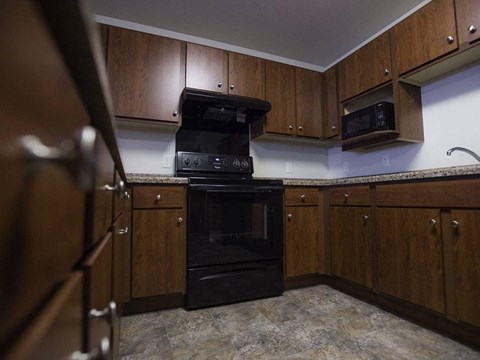 A kitchen with a black oven and wooden cabinets.
