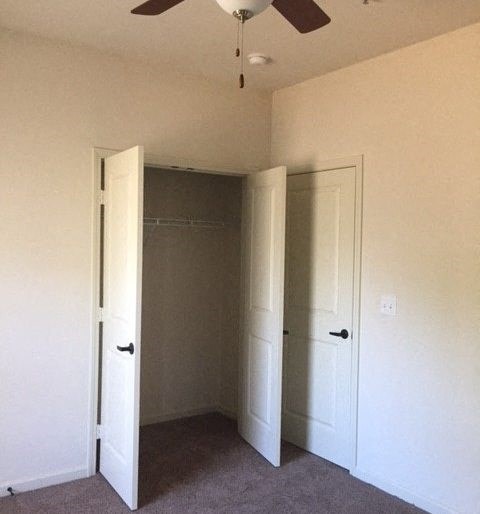an empty room with two doors and a ceiling fan