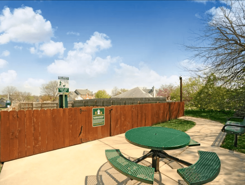 a patio with a table and chairs in front of a wooden fence