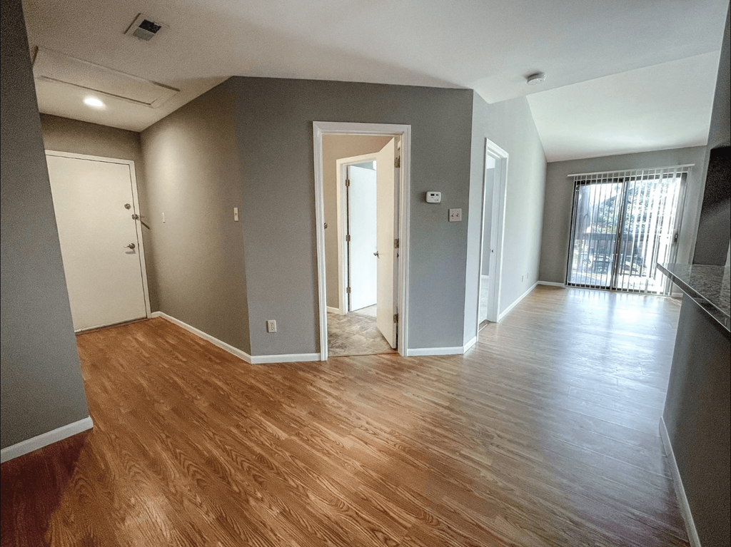 a living room with a hard wood floor and grey walls