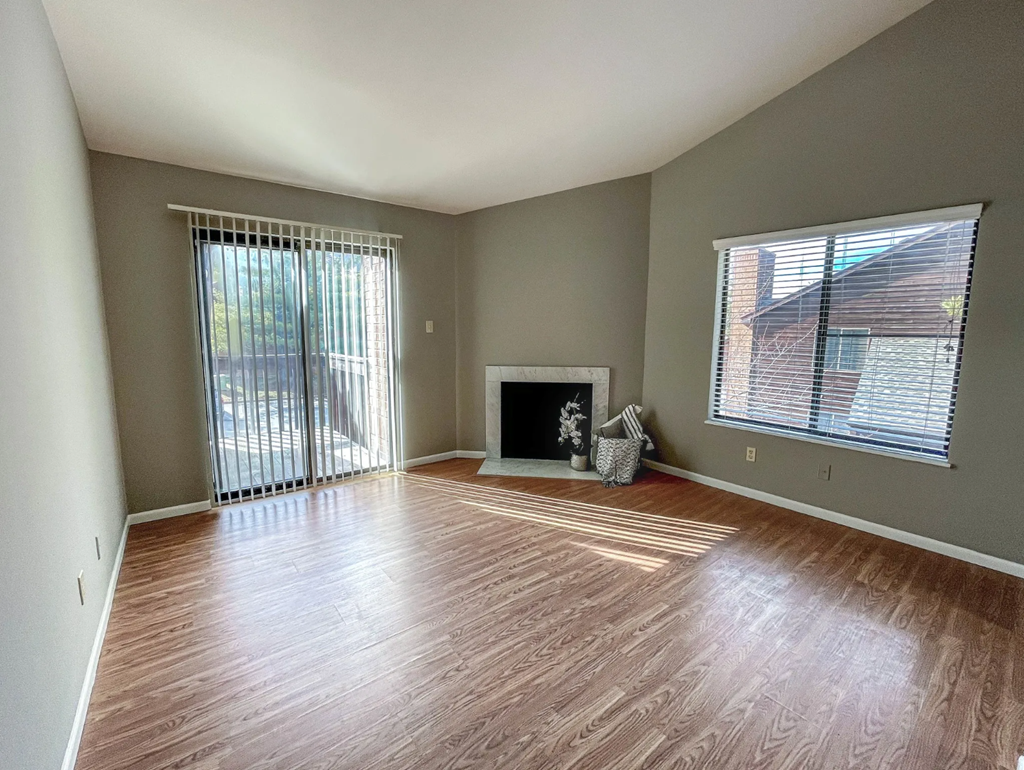 an empty living room with wood floors and a fireplace