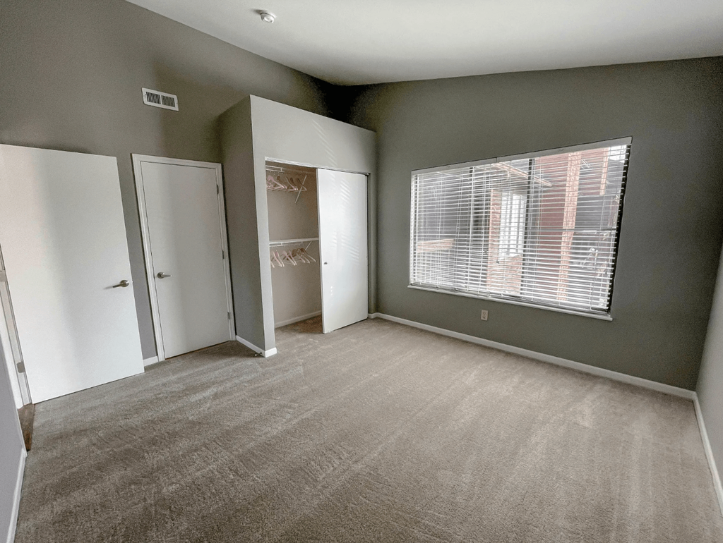 an empty room with a large window and a closet