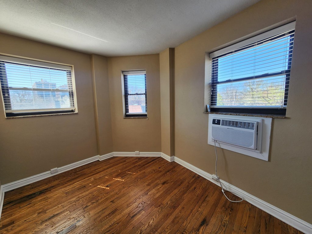A room with wooden floors and two windowsat Convent Gardens Apartments, St. Louis, MO, 63108.