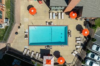 An aerial view of a pool surrounded by chairs and umbrellas.