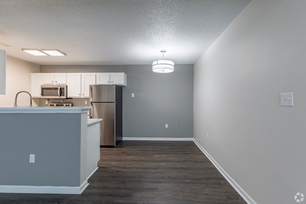 A kitchen with a refrigerator, microwave, and cabinets.