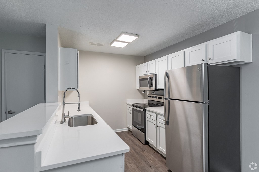 A kitchen with white countertops and stainless steel appliances.