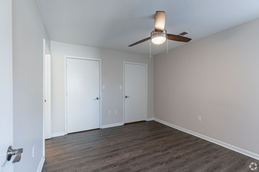 A room with a ceiling fan and three doors.