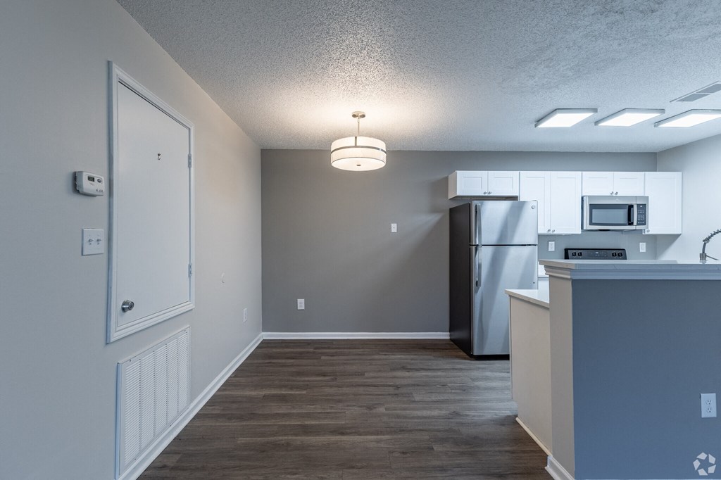 A kitchen with a refrigerator, microwave, and a counter.