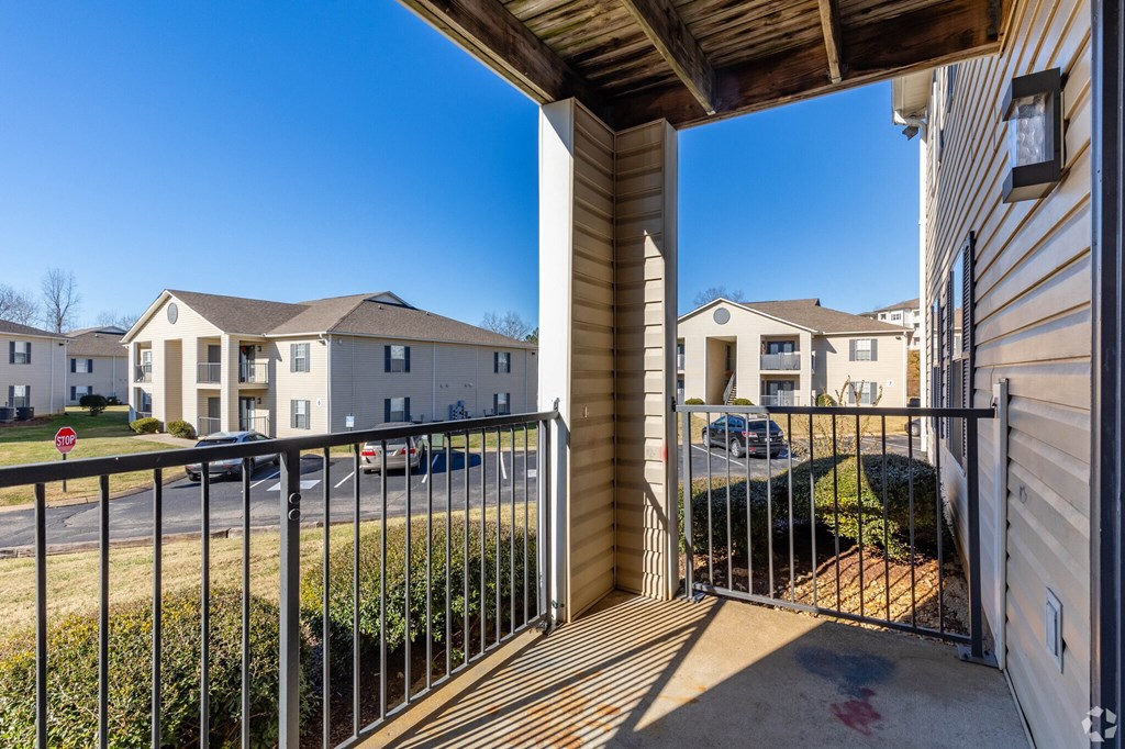 A view from a balcony looking out at a residential area with houses and a clear blue sky.