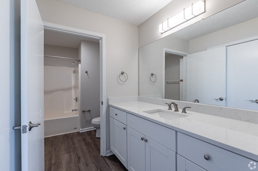 A bathroom with a white sink, a white counter, and a white door.