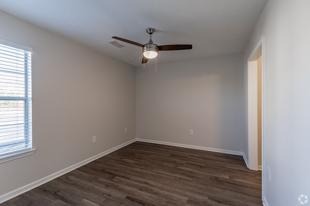 A room with a ceiling fan and wooden flooring.