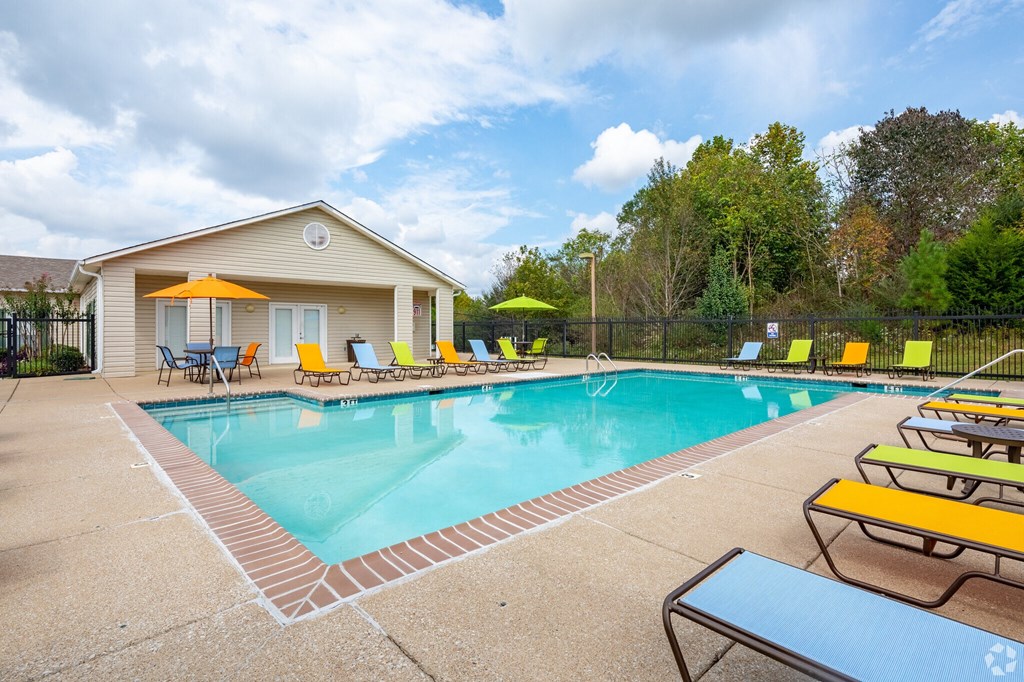 A pool area with a house and chairs.