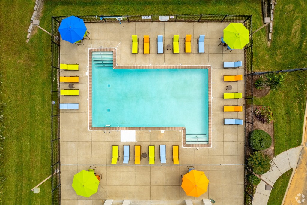 An aerial view of a swimming pool surrounded by sun loungers and umbrellas.