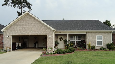 a brick house with a driveway and a garage door open