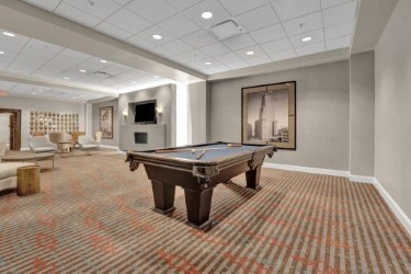 A pool table is in the middle of a room with a carpeted floor.