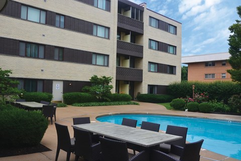 A poolside table and chairs are set up outside a building.