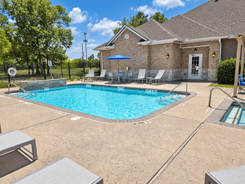 A pool with a blue umbrella and chairs around it.
