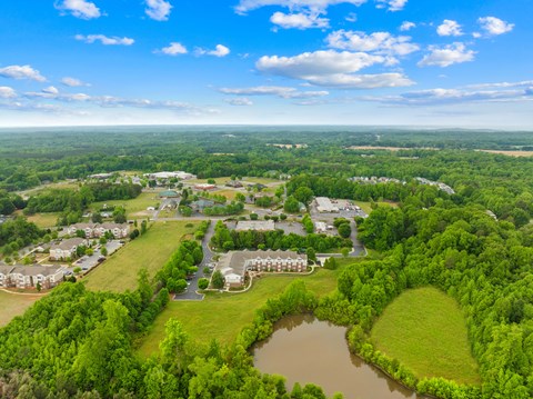 A bird's eye view of a residential area with a pond in the foreground.