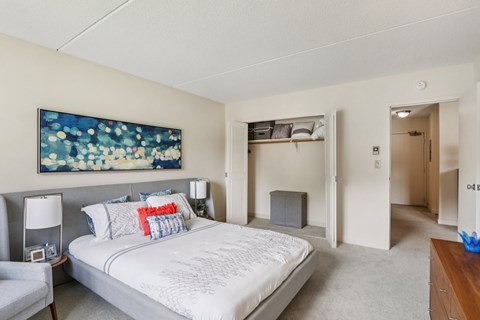 A bedroom with a large bed and a painting on the wall.