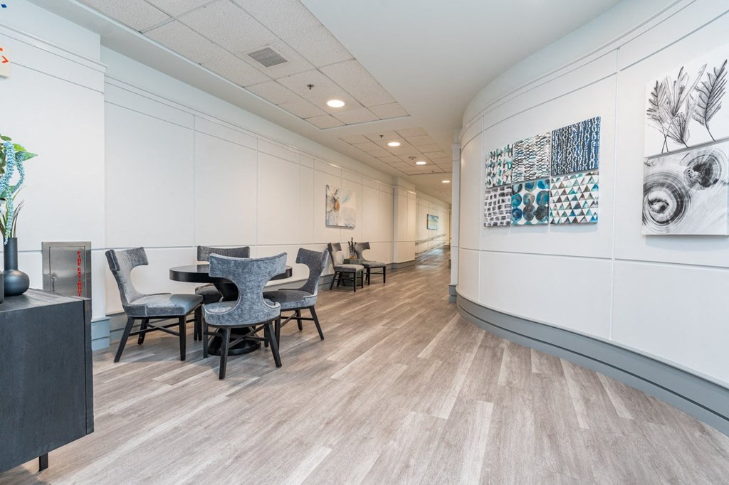 a room with a table and chairs on the left and a hallway on the right