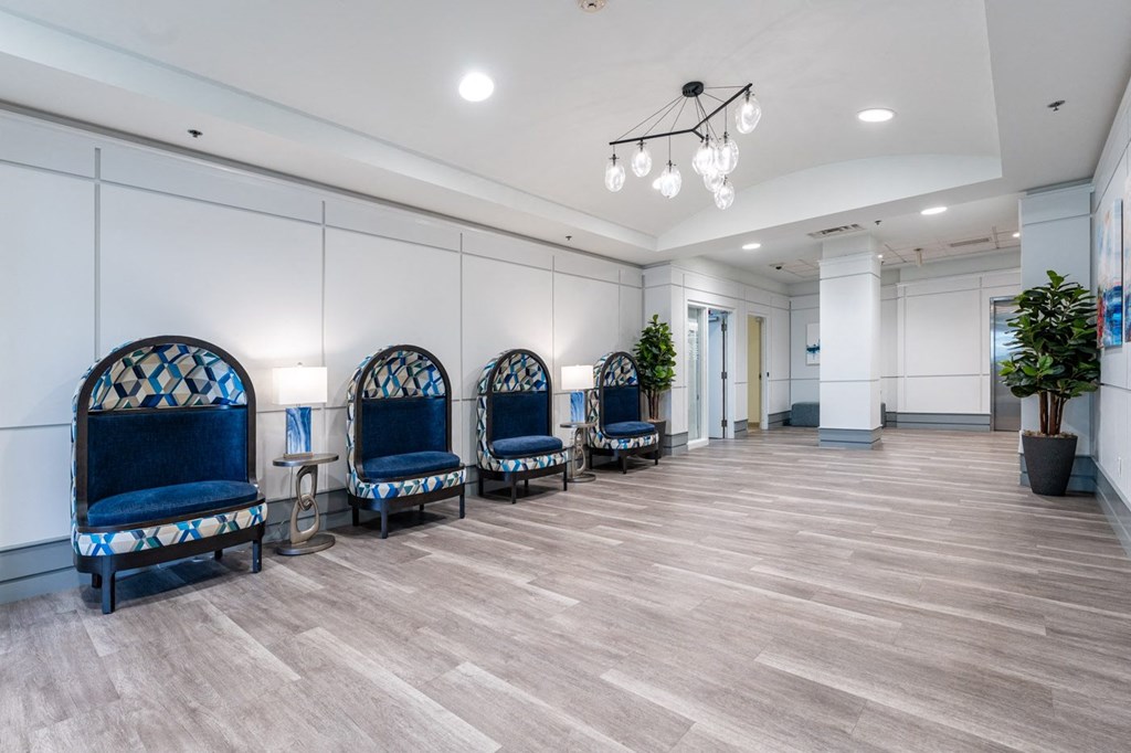 a room with a row of blue chairs and a chandelier