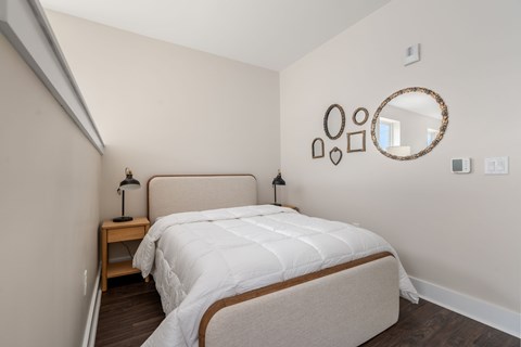 A bedroom with a large bed and a mirror on the wall.