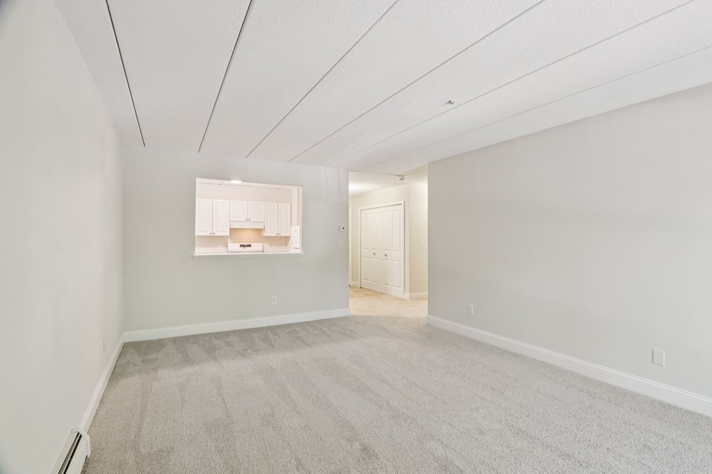 A large empty room with carpeted floor and white walls.