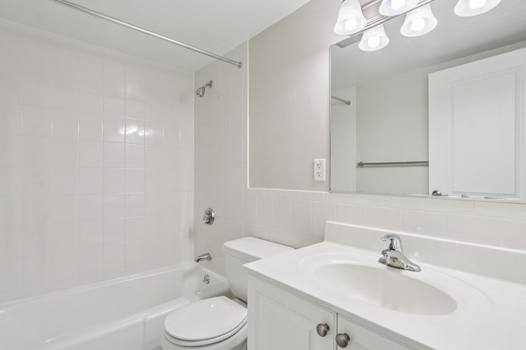 A white bathroom with a toilet, sink, and bathtub.