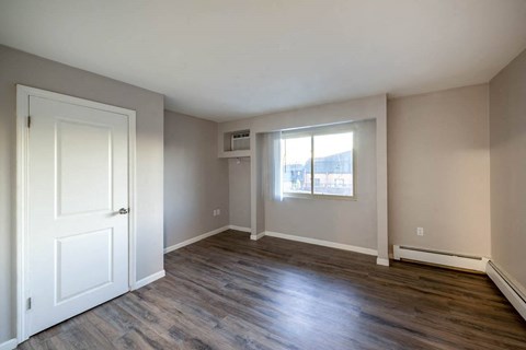 an empty living room with a white door and a window