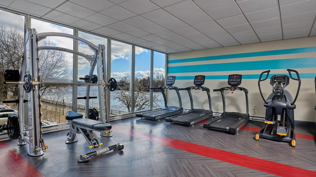 The atherton gym with cardio equipment, smith machine, bench, elliptical, view of river