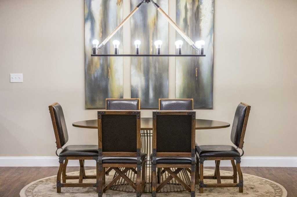 A dining area with a sophisticated chandelier and contemporary art piece on the wall, enhancing the upscale feel of Webster Woods.
