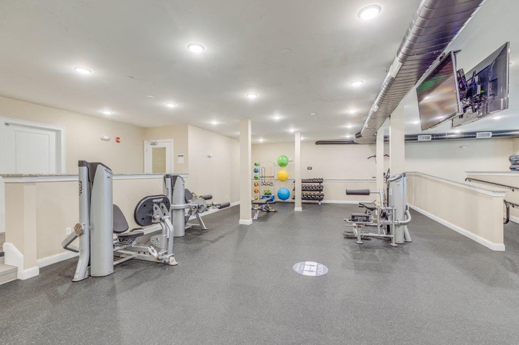 A fully-equipped fitness center with a variety of machines and bright lighting, perfect for resident workouts at Webster Woods.