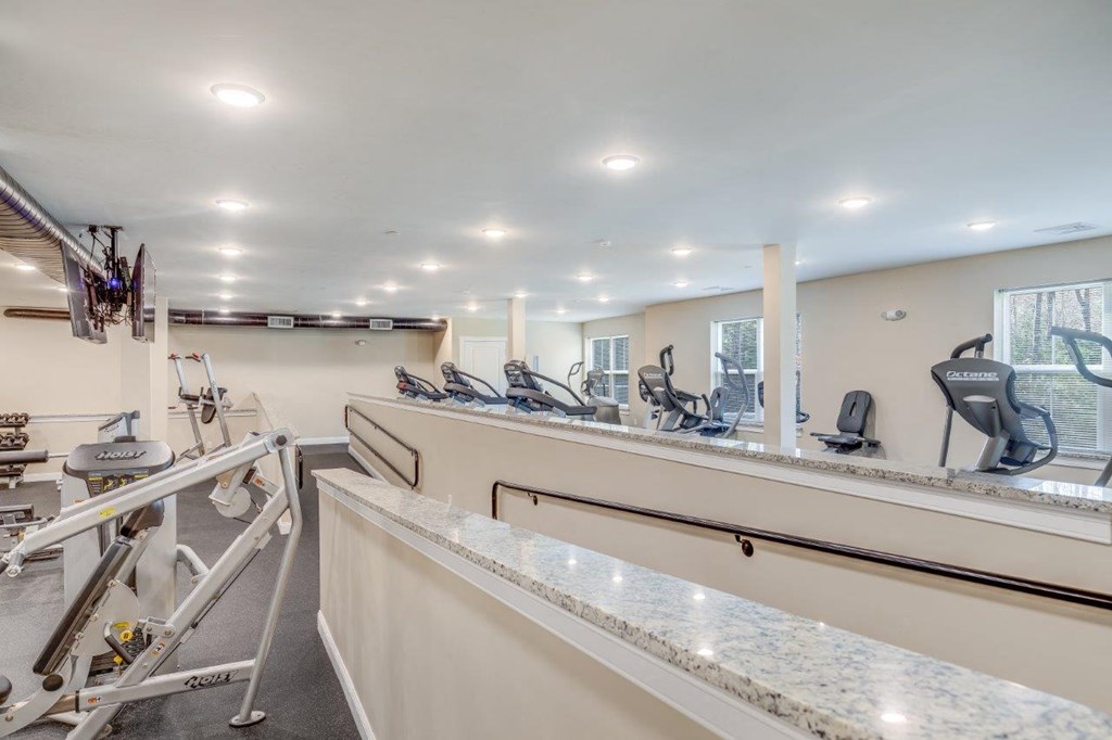 A fully-equipped fitness center with a variety of machines and bright lighting, perfect for resident workouts at Webster Woods.