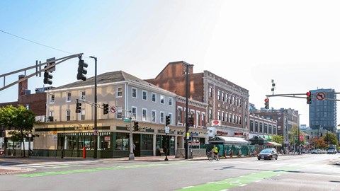Street view of Central Square featuring Starbucks, local shops, and pedestrian activity near 929 Mass Apartments in Cambridge MA.