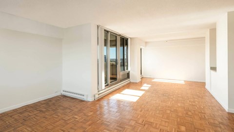 Spacious living area with parquet flooring and floor-to-ceiling windows leading to a private balcony at 929 Mass Apartments in Cambridge MA.