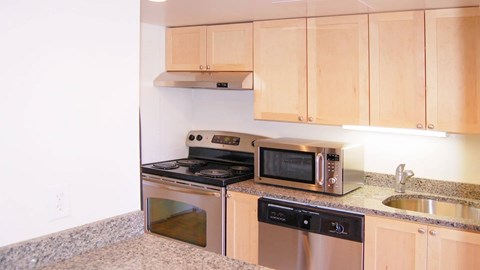 Modern kitchen with stainless steel appliances, granite countertops, and light wood cabinets.