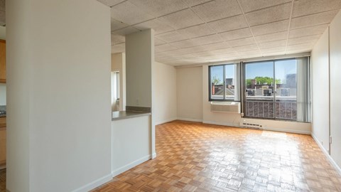 Spacious living and dining area with parquet floors, large windows, and an open layout.