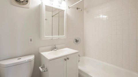 Bathroom with white vanity, tiled tub surround, and chrome fixtures at 929 Mass Apartments in Cambridge MA.