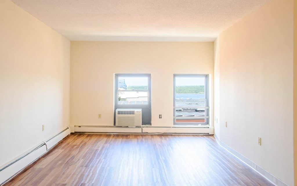 A room with wooden floors and two windows.