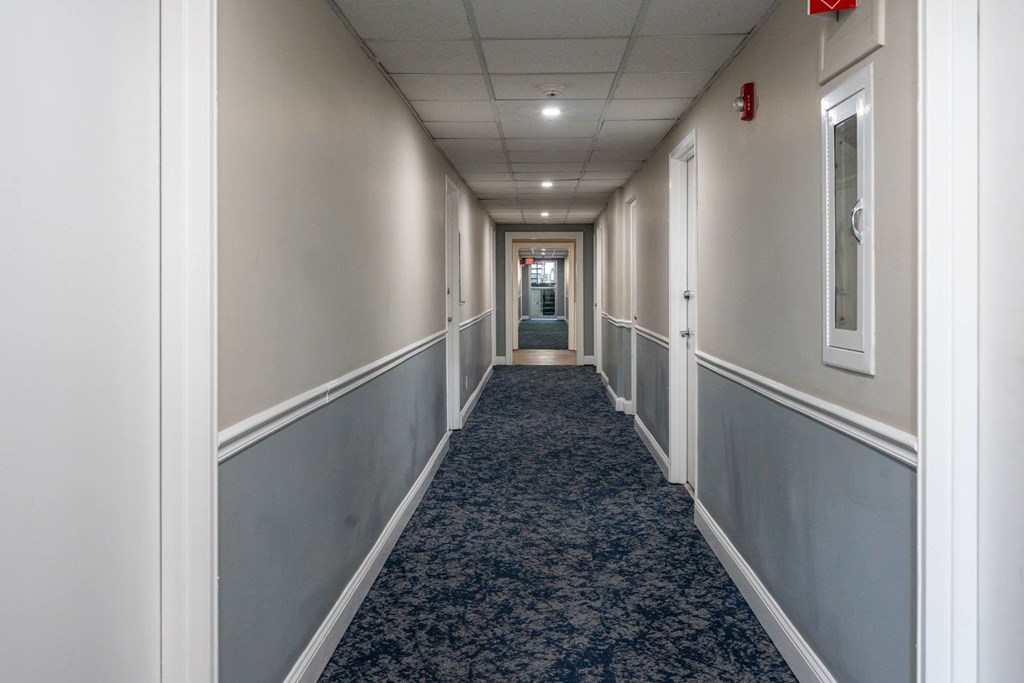 A long hallway with a carpeted floor and white walls.