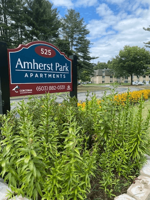a sign for amherst park apartments in front of a garden