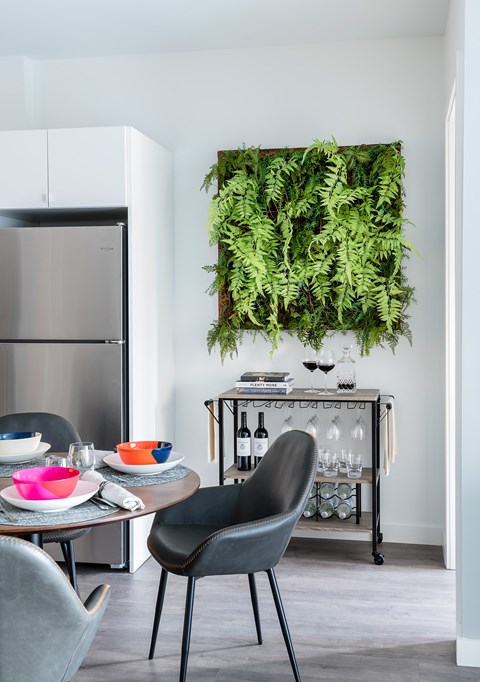 A modern kitchen with a table and chairs and a green plant hanging on the wall.