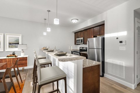 a kitchen with a bar and chairs and a stainless steel refrigerator
