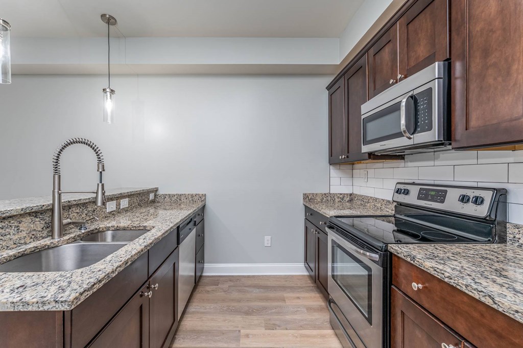A kitchen with dark wood cabinets and granite countertops.