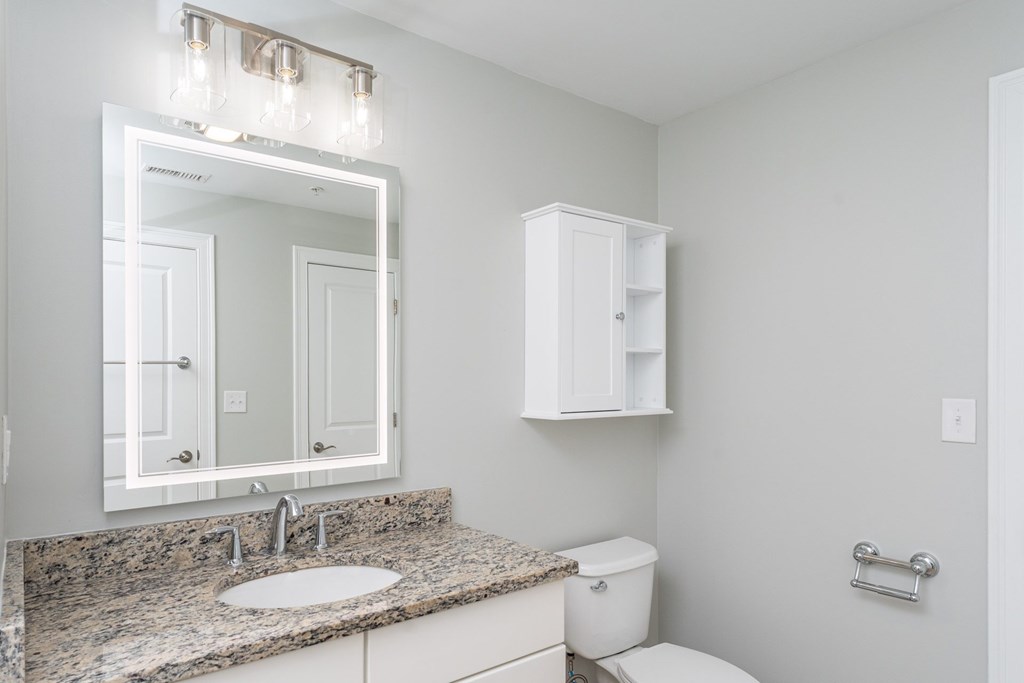 A bathroom with a granite countertop and a white cabinet.