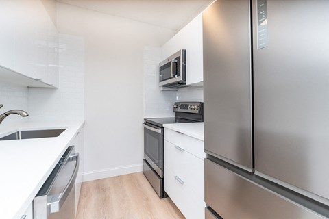 a modern kitchen with stainless steel appliances and white counter tops